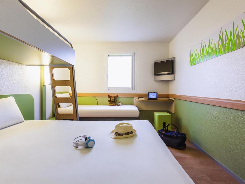 - une chambre avec 2 lits et des lits superposés avec un chapeau dans l'établissement ibis budget Marne la Vallée Pontault Combault, à Pontault-Combault