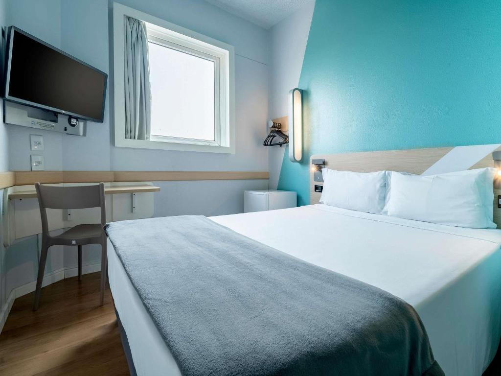 a hotel room with a large bed and a desk at ibis budget Sao Paulo Jardins in Sao Paulo