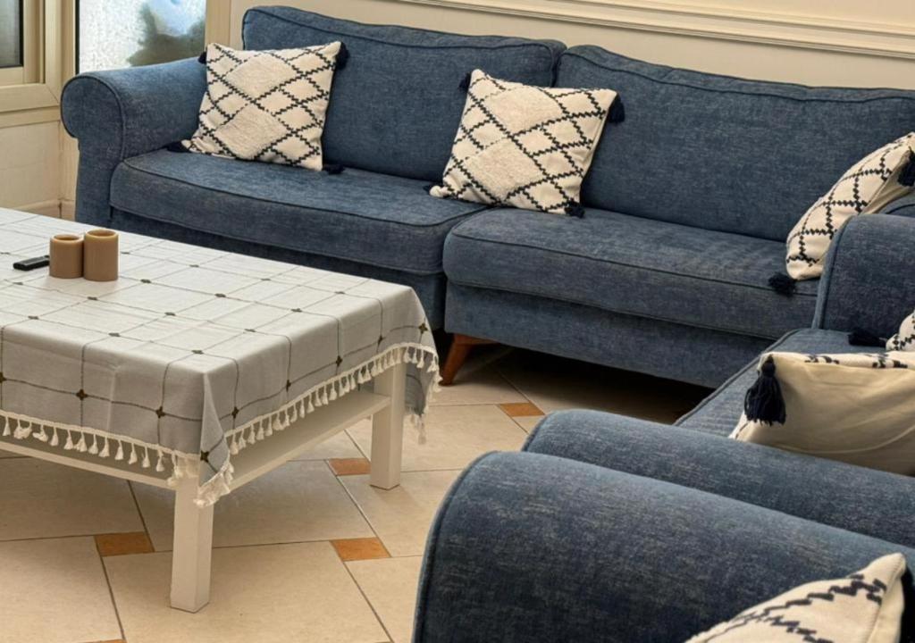 a living room with blue couches and a table at High Altitude Makkah - Aziziya Spacious Flat in Makkah
