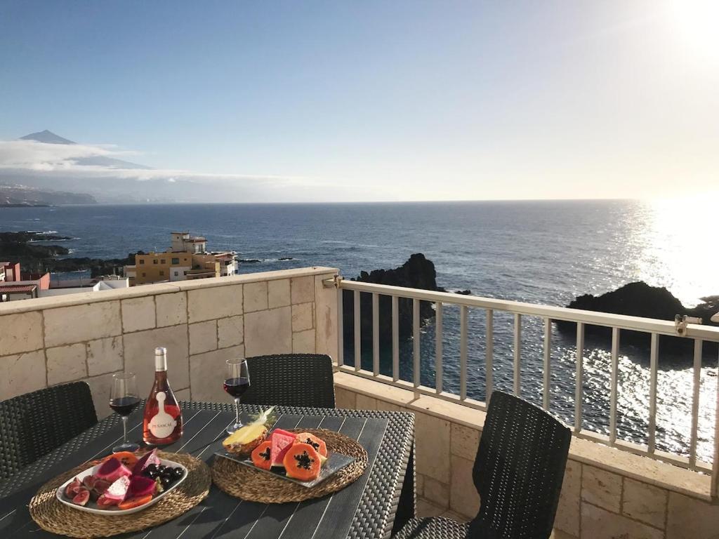 a table with food and wine on a balcony with the ocean at WONDERFUL Sea Views El Pris in El Pris