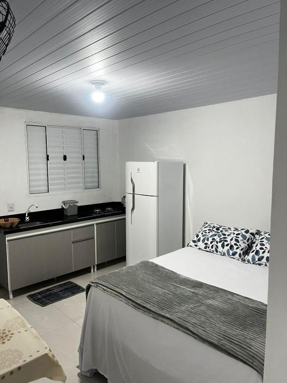 a kitchen with a bed and a white refrigerator at Brisa do Forte in São Francisco do Sul
