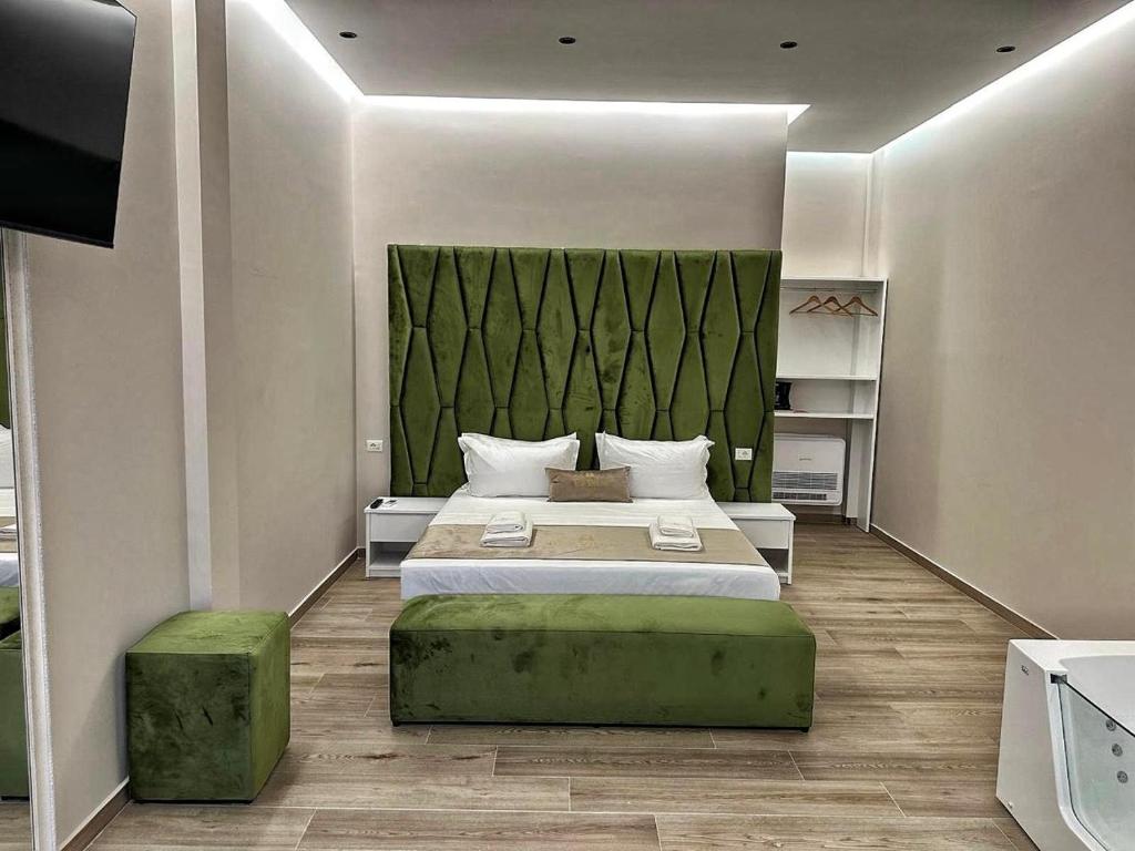 a bedroom with a large bed with a green headboard at Lumeris lakeview Suites and SPA in Rubjekë