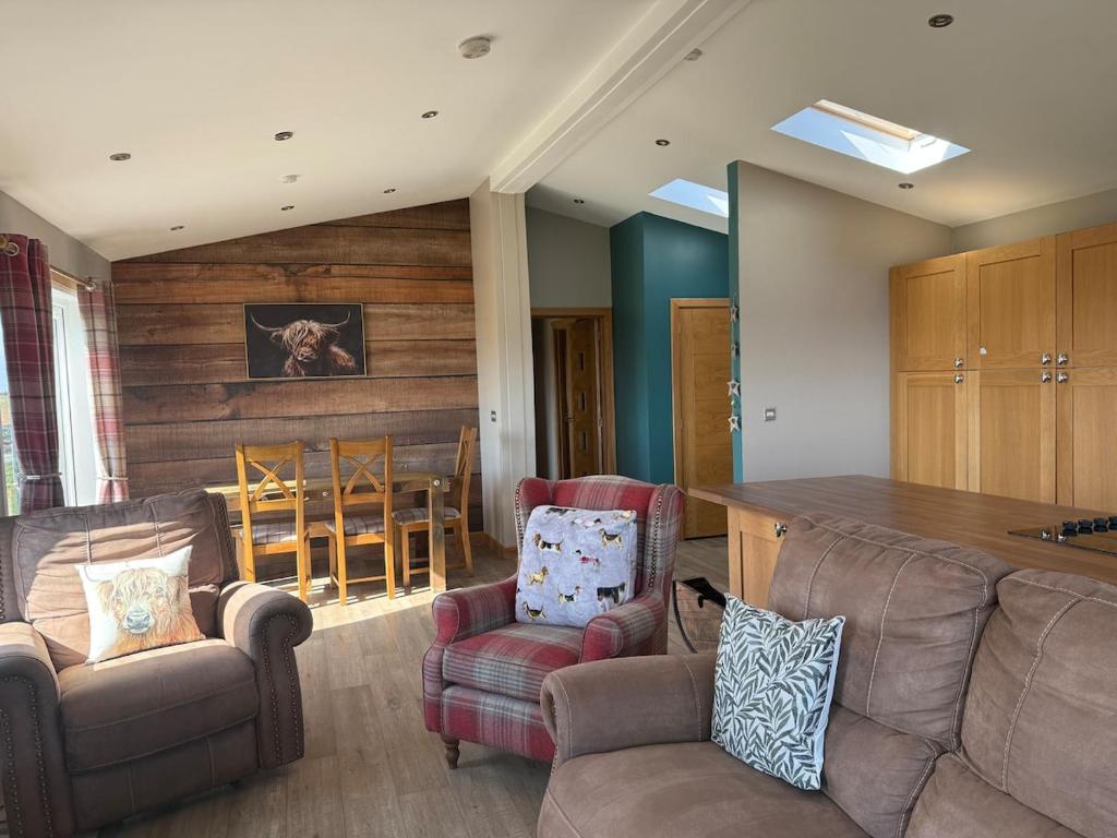 a living room with a couch and chairs and a table at Drovers Lodge, farm retreat in rural Lanarkshire, family and pet friendly, onsite craft distillery, perfect location for exploring central Scotland in Forth