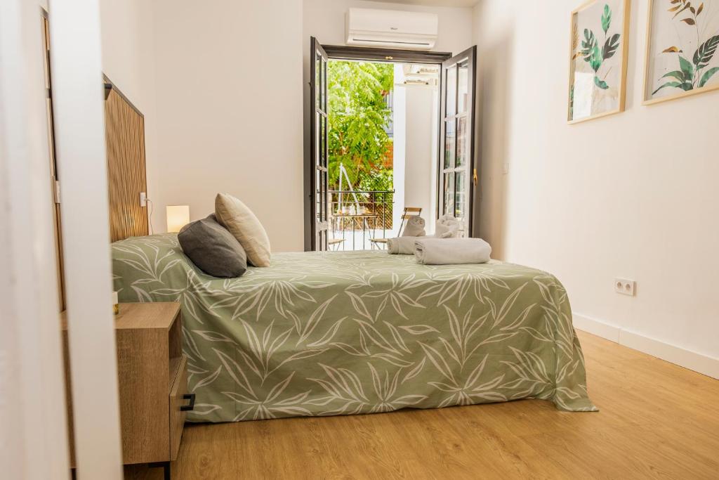 a bedroom with a bed with a green comforter and a window at Apartamento en centro de Cazorla con vista a la montaña in Cazorla