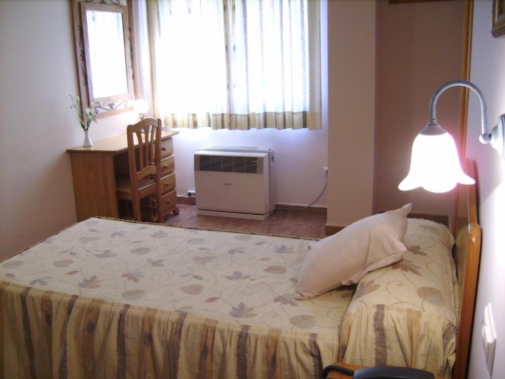 sypialnia z łóżkiem, lampą i oknem w obiekcie Hotel Mesón el Castillo w mieście Bañeres de Mariola