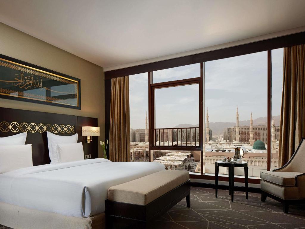 a bedroom with a large bed and a large window at Zamzam Pullman Madina in Al Madinah