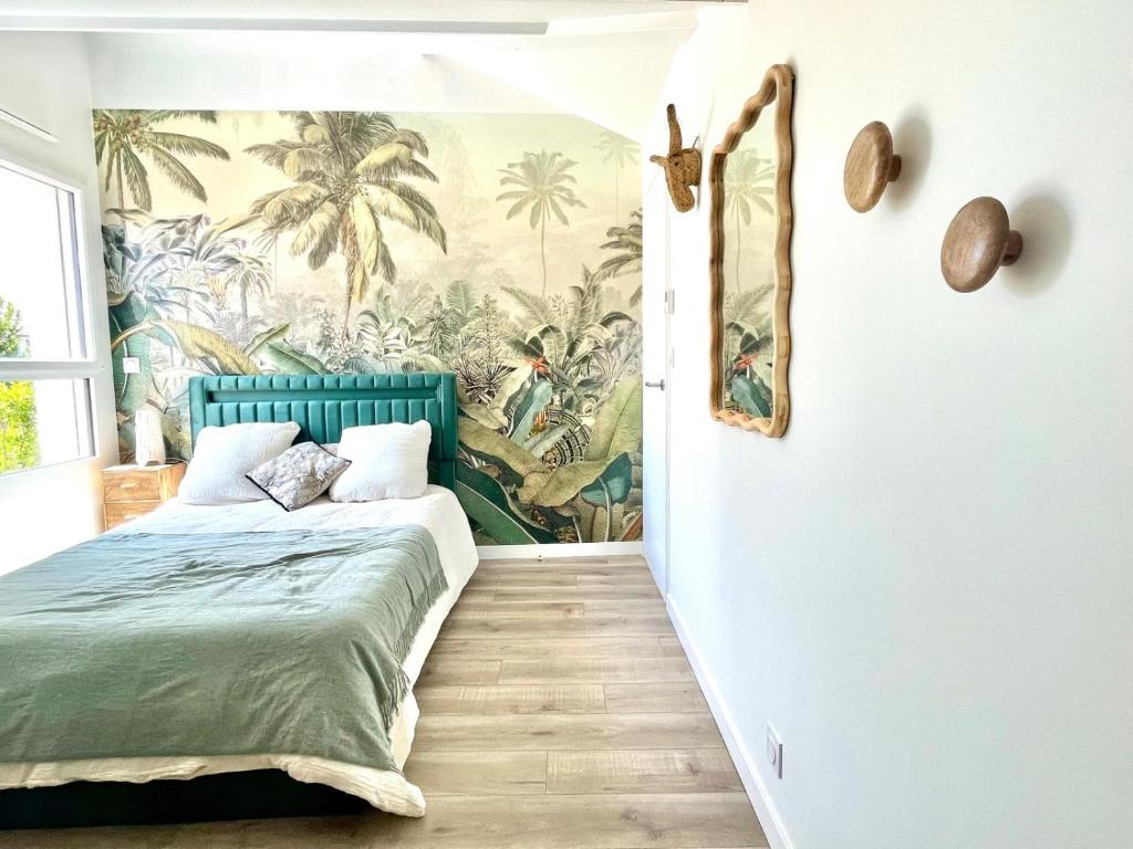a bedroom with a green bed and palm trees mural at Jungle, chambre spacieuse au coeur des sables in Les Sables-dʼOlonne