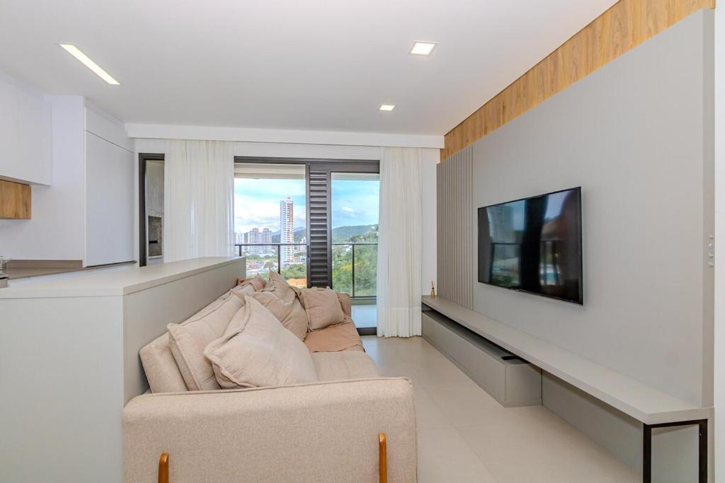 a living room with a couch and a flat screen tv at Praia Brava - Central entre Itajaí e BC - 2 Qts e Ar in Itajaí