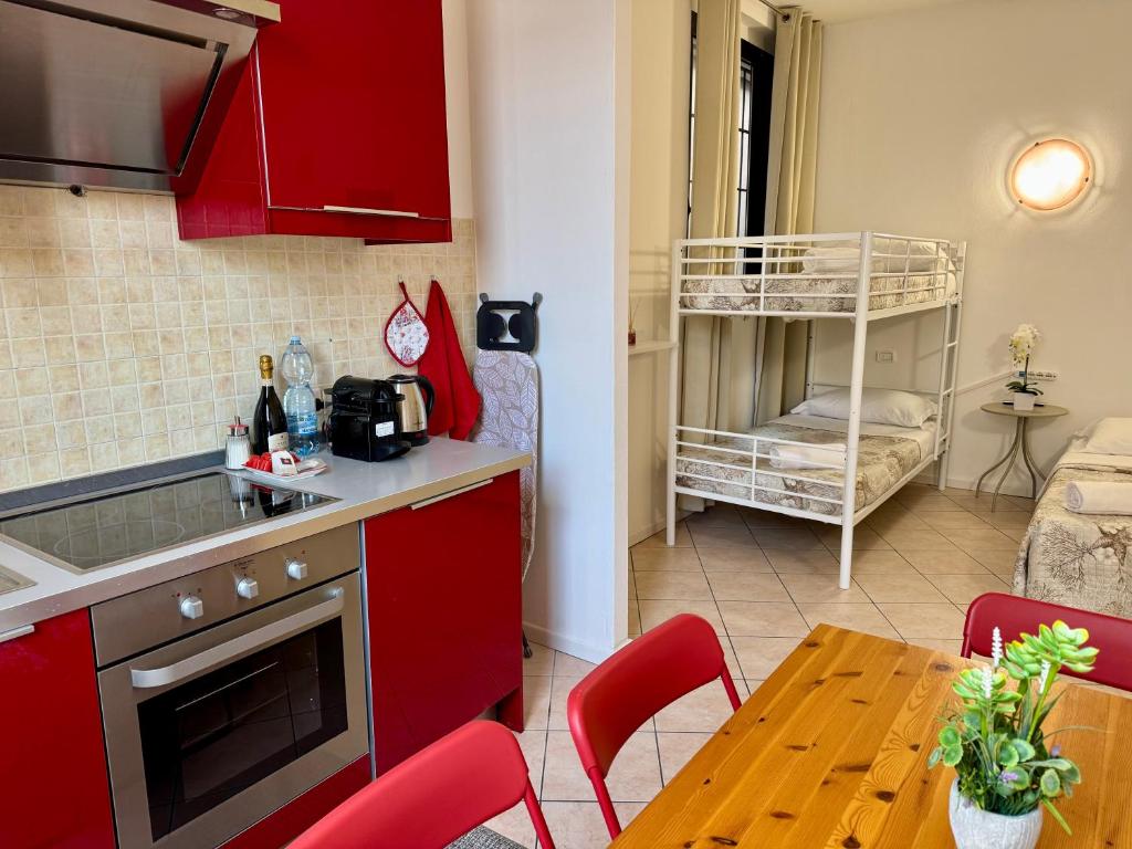 a kitchen with red cabinets and a table with red chairs at Aparthotel Dergano 3 near metro stop in Milan