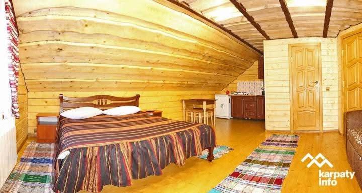 a bedroom with a bed in a log cabin at Лісова тиша Сімейні номера in Synevyrsʼka Polyana