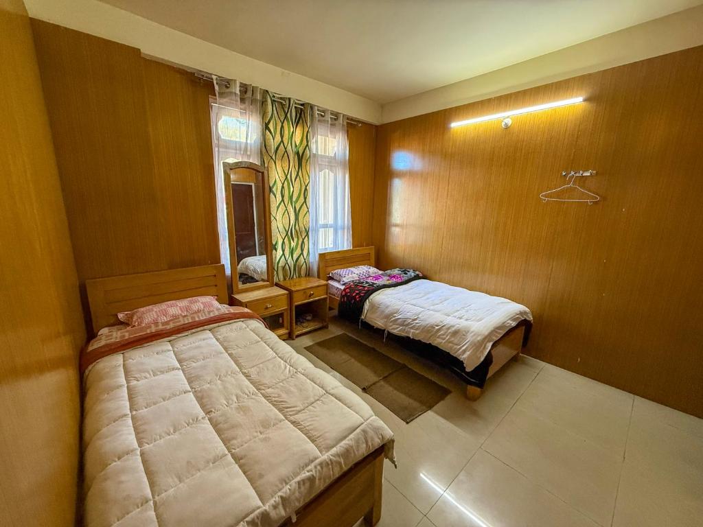 a bedroom with two beds and a window in it at JD House in Tawang