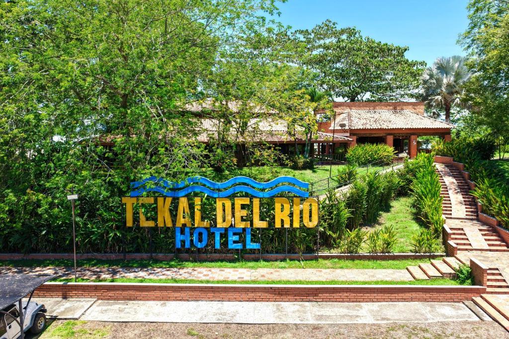 a sign that says tka del mmo hotel in a garden at Hotel Tekal del Rio in Puerto Boyacá