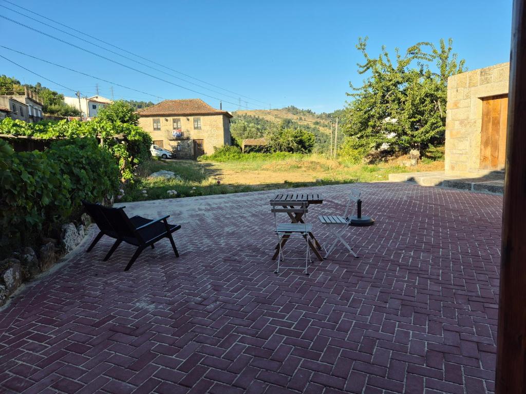 Deux bancs et deux tables sur une terrasse en briques dans l'établissement Charming Douro Valley Stone Home, à Coura