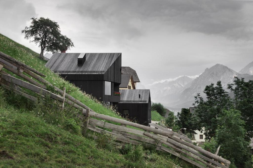 una casa su una collina con una recinzione di legno di Chalet La Pedevilla a San Vigilio Di Marebbe