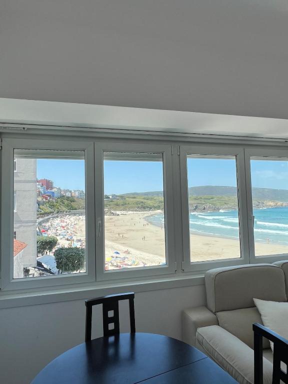 a living room with three windows and a view of a beach at Marusía apartamento in Malpica
