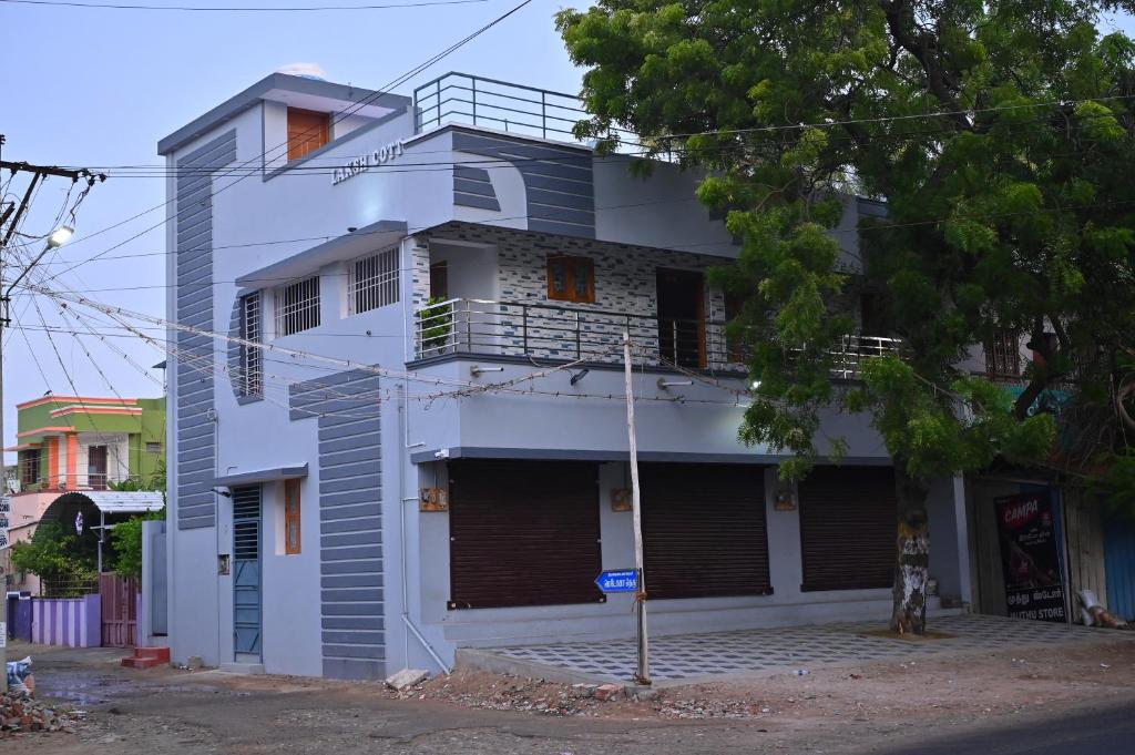 a white building with a balcony on a street at LAKSH COTT Home Stay in Arumuganeri
