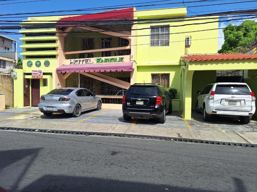 two cars parked in a parking lot in front of a building at Hotel Enrique I Gazcue, Bed and Breakfast in Santo Domingo