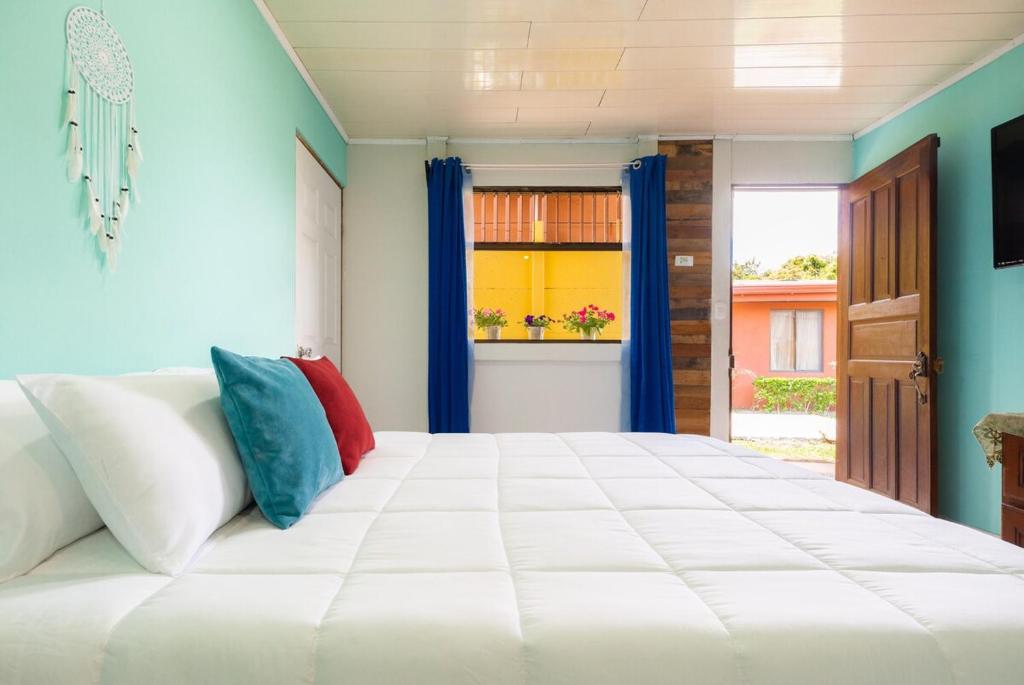 a bedroom with a large white bed with colorful pillows at Casa Mandala by Dreamcatcher in Sarchí