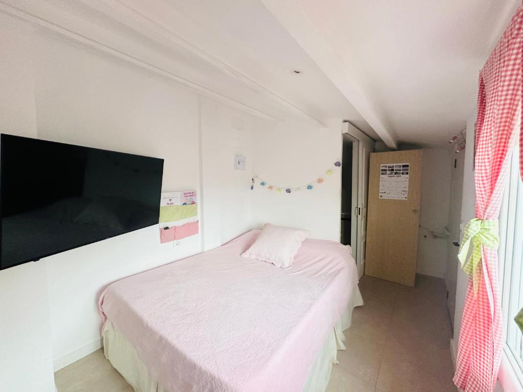 Habitación pequeña con cama y TV de pantalla plana. en Habitación con baño y cocina, en Caudiel