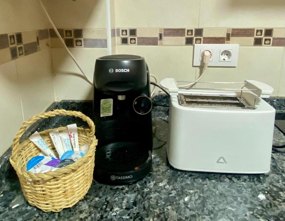 a coffee maker next to a toaster and a basket on a counter at El nido del búho Soportujar in Soportújar