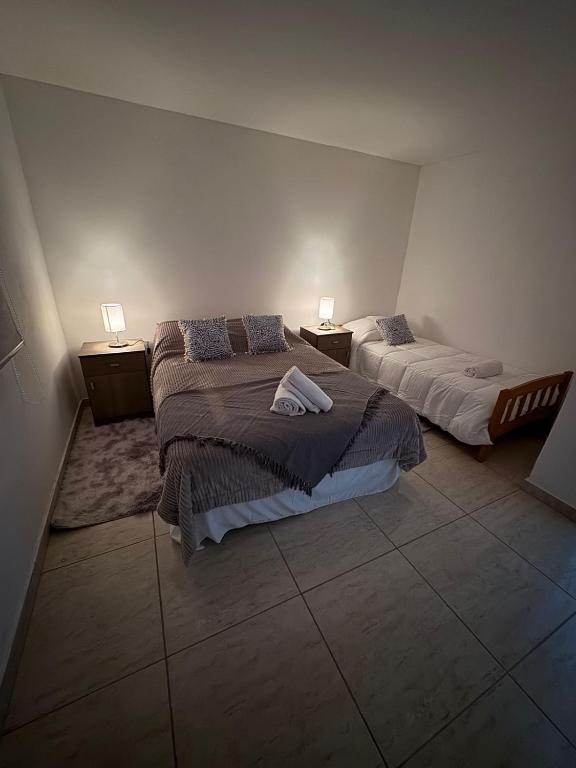 a bedroom with two beds and two lamps on the wall at Apart Ayres -Planta alta in Río Gallegos
