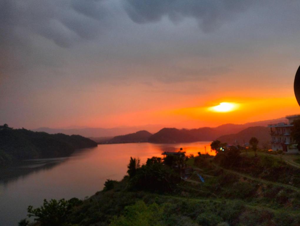 a sunset over a river with the sun setting at Hotel bright moon lake in Deorāli