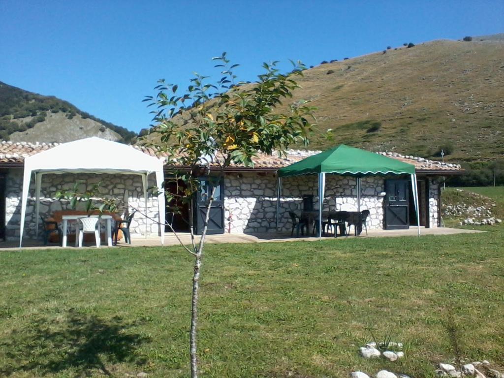 ein Haus mit einem Tisch und einem grünen Sonnenschirm in der Unterkunft Chalet Vista Lago in San Gregorio