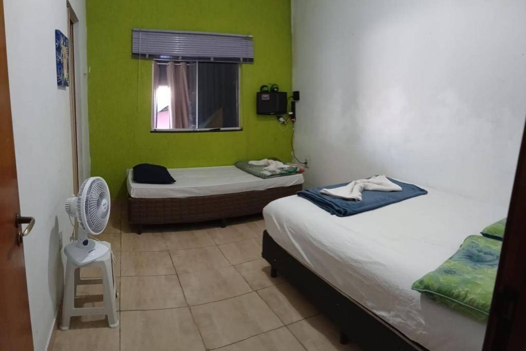 a small room with two beds and a fan at Jams Hostel - Pousada perto da Ufcat in Catalão