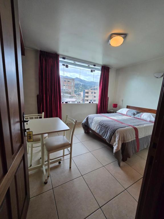 a bedroom with a bed and a desk and a window at Amaru Peru Hotel in Huaraz