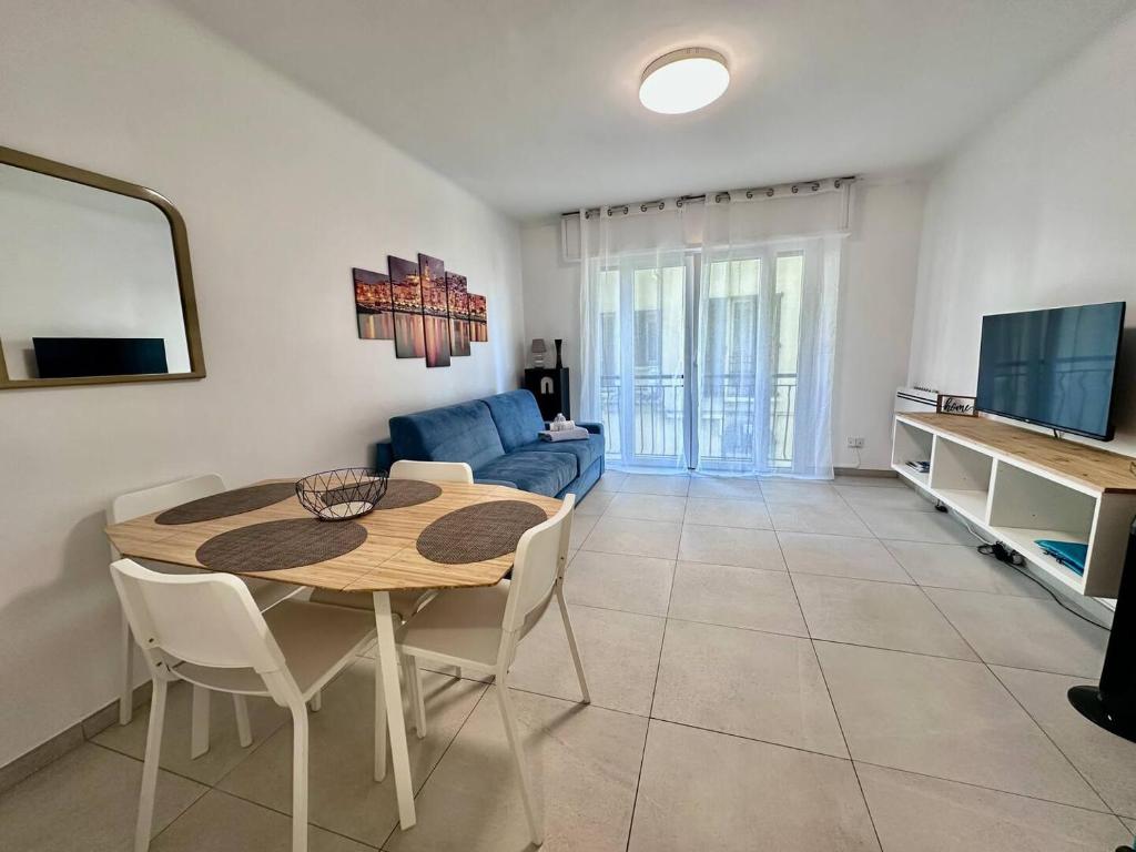 a living room with a table and a blue couch at L'Espadon - vue mer, proche plage et gare in Menton