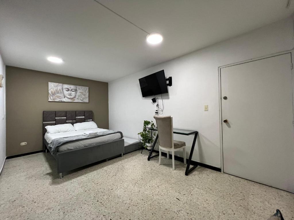 a bedroom with a bed and a chair and a television at APARTAMENTO ESTADIO in Cali