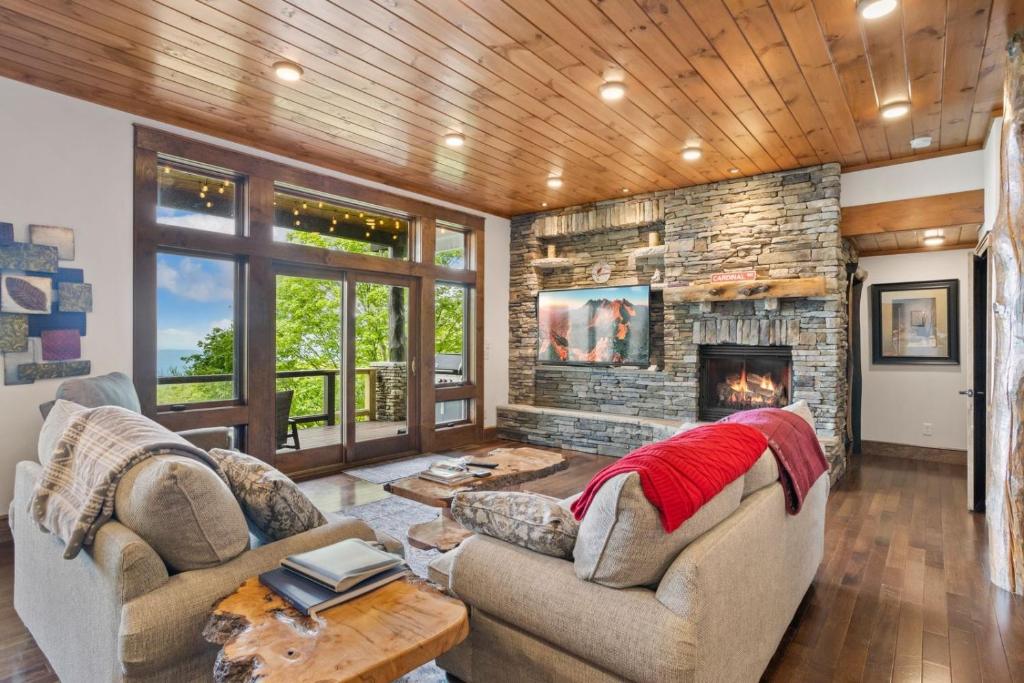 a living room with two couches and a stone fireplace at Cardinal Perch in Beech Mountain