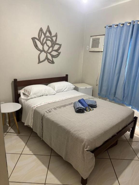 a bedroom with a large bed with a blue curtain at Casa Maju Suítes in Búzios