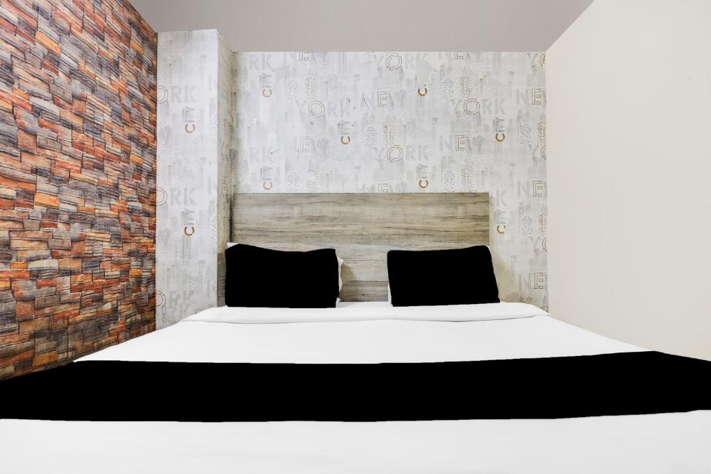 een slaapkamer met een wit bed en een bakstenen muur bij Super Hotel O Royal Green in New Delhi
