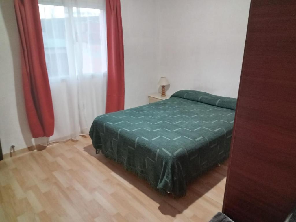 Un dormitorio con una cama verde y una ventana. en Refugio del Viento, en Gobernador Gregores