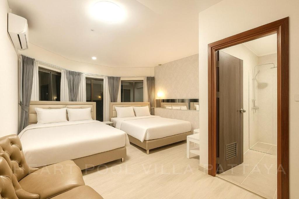 una habitación de hotel con dos camas y un sofá en Heart Pool Villa Pattaya, en Pattaya South