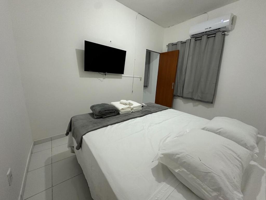 ein weißes Schlafzimmer mit Bett und Flachbildfernseher in der Unterkunft Apartamento Flat 303 COP30 in Belém