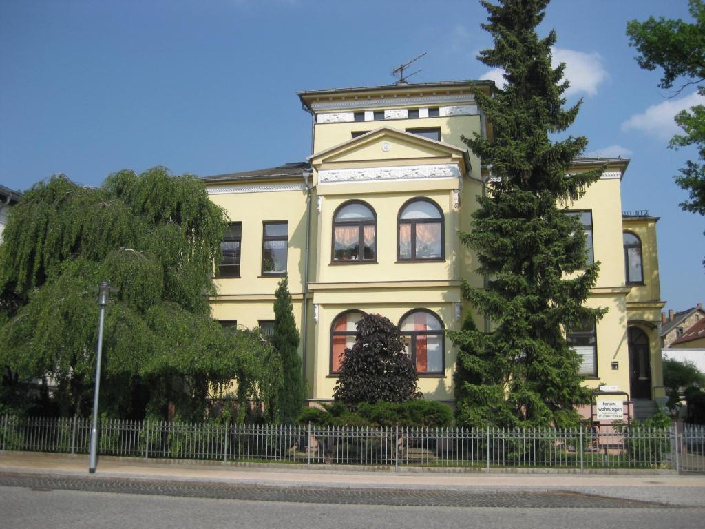 a yellow house with a tree in front of it at Villa Amilia - Ferienwohnung 2 in Waren
