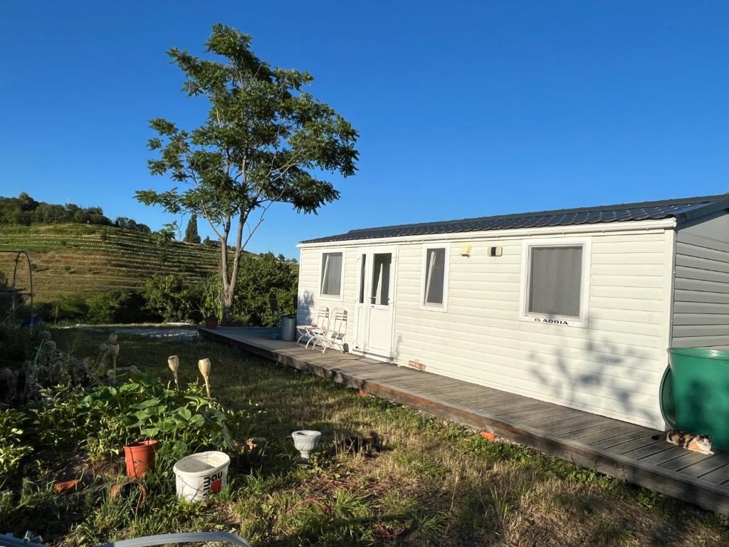 a white tiny house with a wooden deck at Romantisches Tiny House mit Pool and Air Condition in Tržec