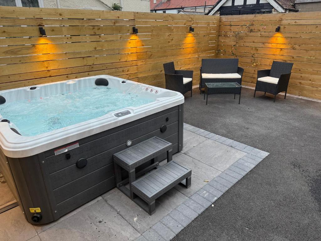 a hot tub in a patio with chairs and a fence at Rhos On Sea Getaway in Rhôs-on-Sea
