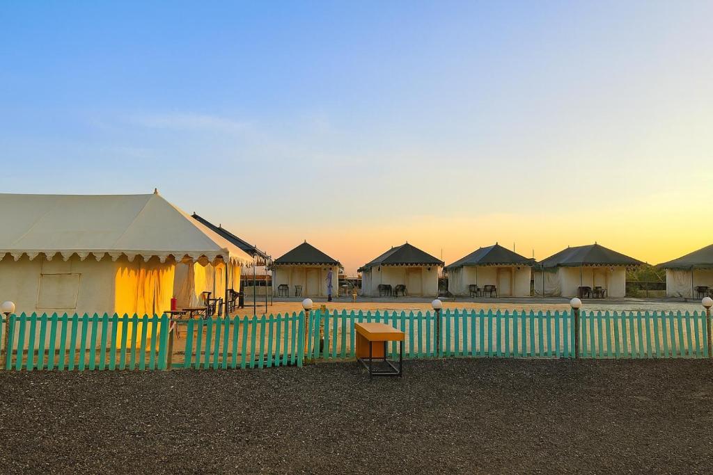 a row of cottages behind a fence with a fence sidx sidx at Stayguru Patgar Tent in Dhordo