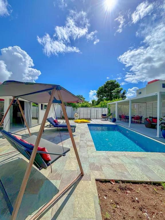 a swimming pool with a hammock next to a house at Villa élégante avec piscine à Cluny Schoelcher in Schœlcher