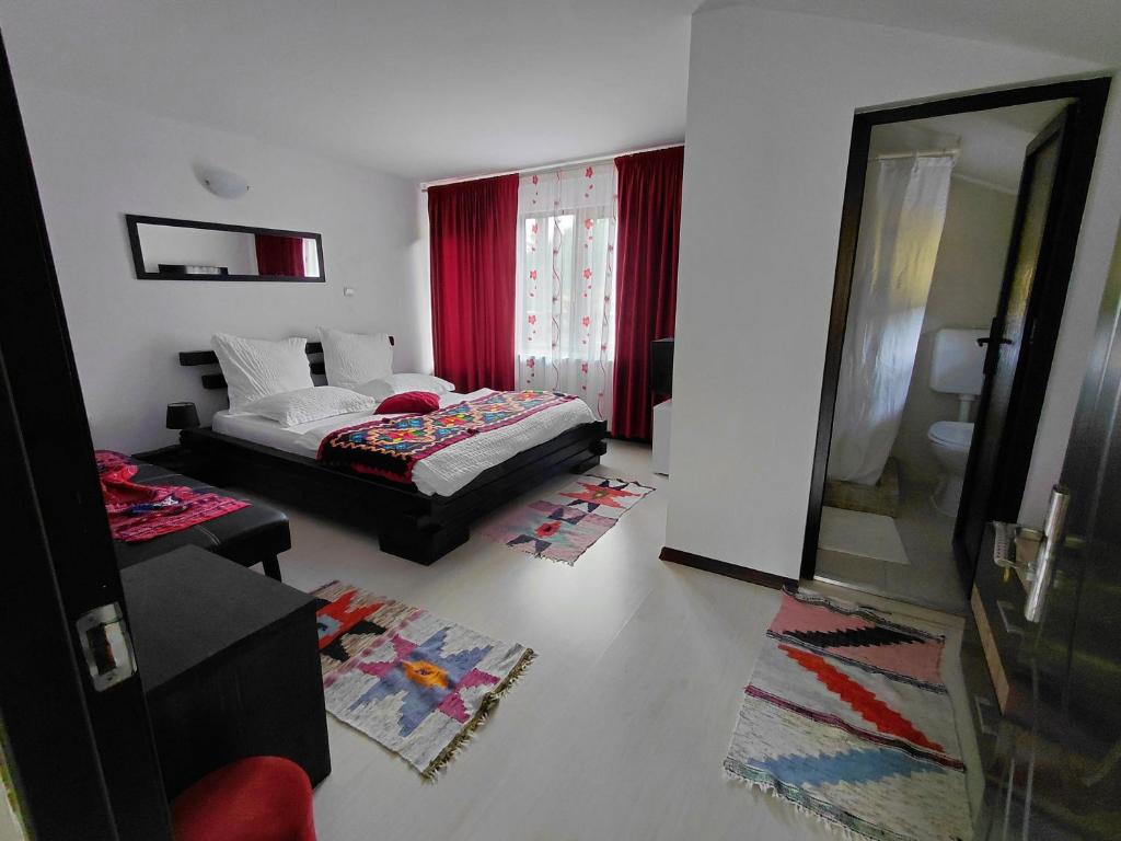 a bedroom with a bed and a mirror and red curtains at Casa Nico Nelu Duplex in Arieşeni