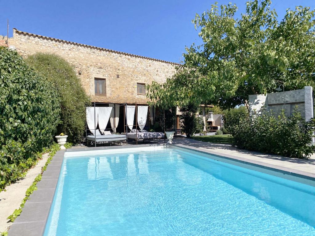 una piscina con due sedie e un edificio di Can Cinto a Vilamacolum