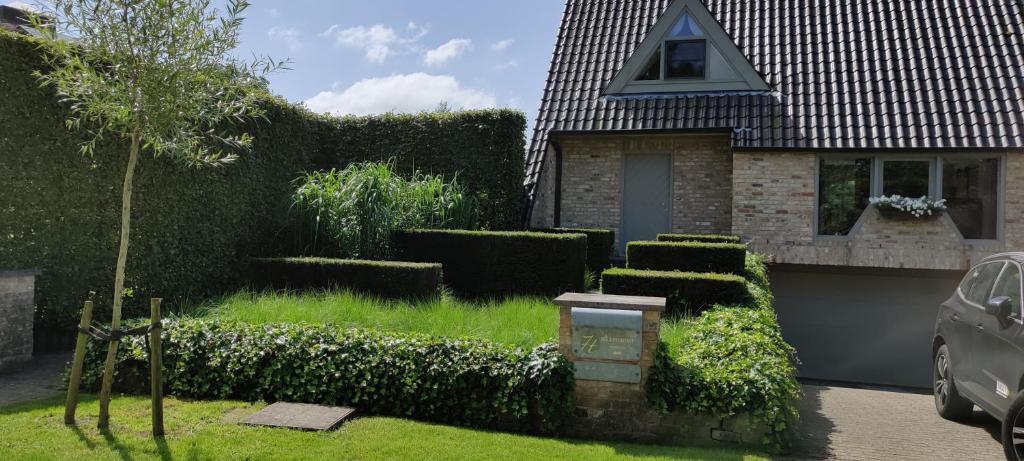 a house with a yard with a hedge at B&B 7T in Bruges