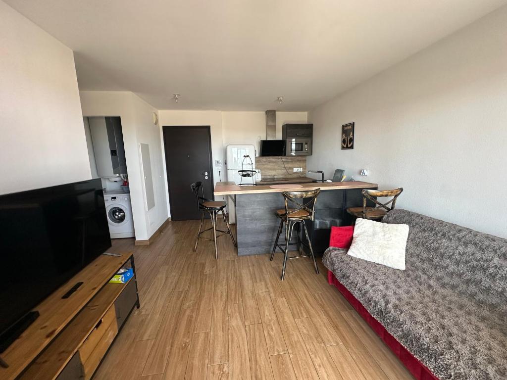 a living room with a couch and a kitchen at Pigonia T2 récent, confort et design à Furiani - à la nuitée in Furiani