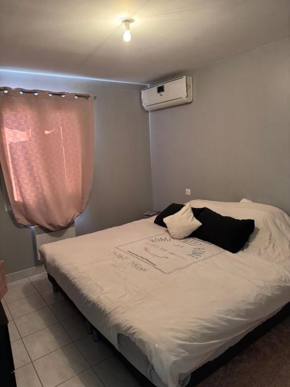 a bed in a room with a pink curtain at Maison verdoyante in Monteux