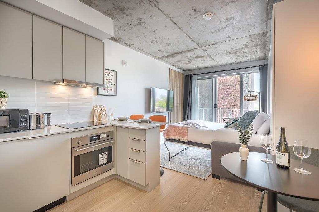 a kitchen and living room with a bed and a table at Urban Hideout - Downtown Haven in Montréal