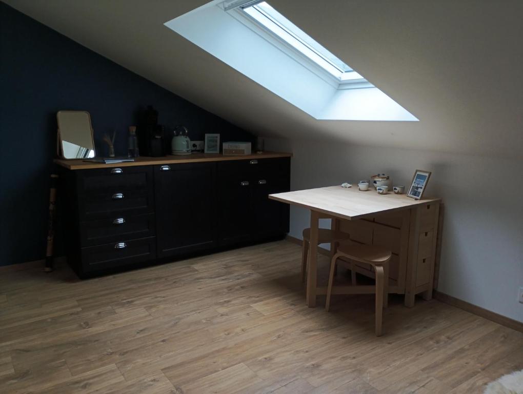 Una habitación con una mesa, una cómoda y una claraboya. en Chambre triple proche plage, en Lancieux