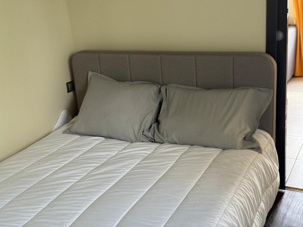 a bed with white sheets and pillows in a bedroom at Charmant appartement in Charnècles
